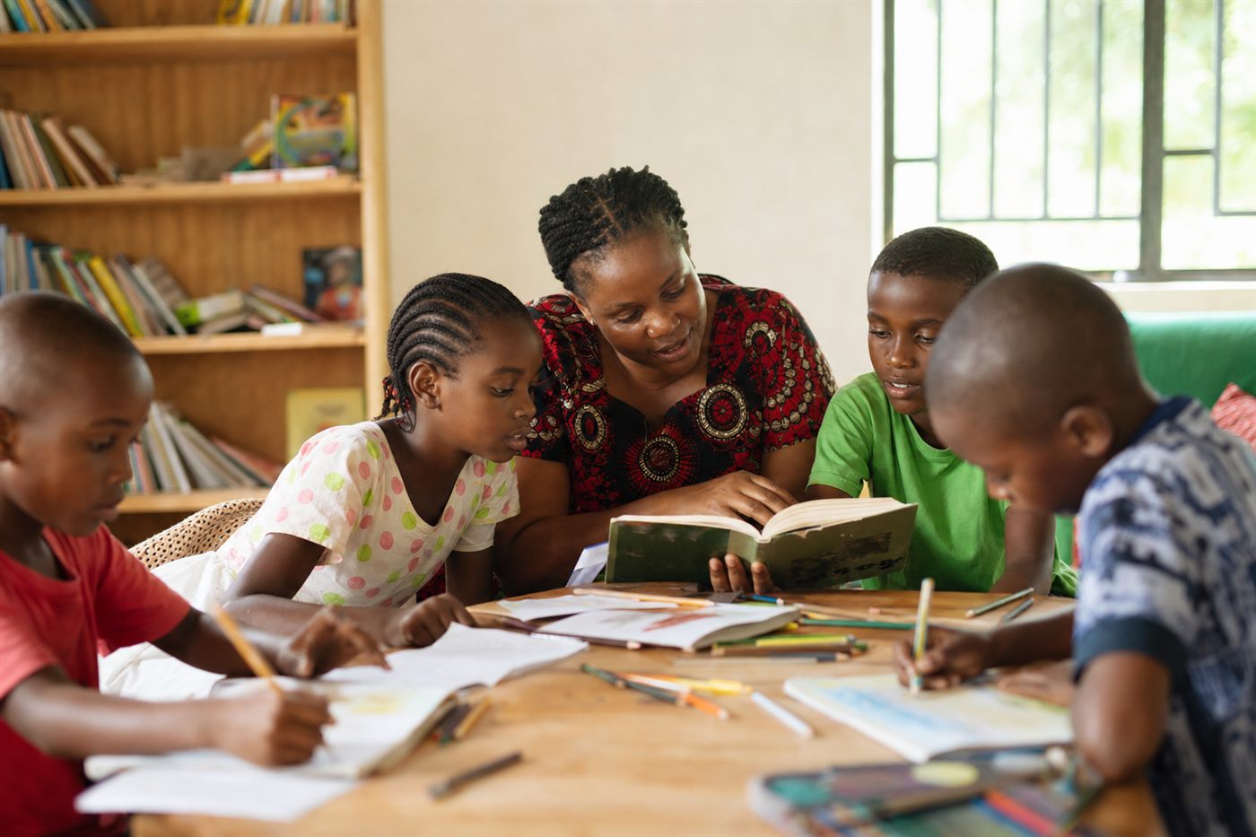 Children reading and drawing with a caregiver